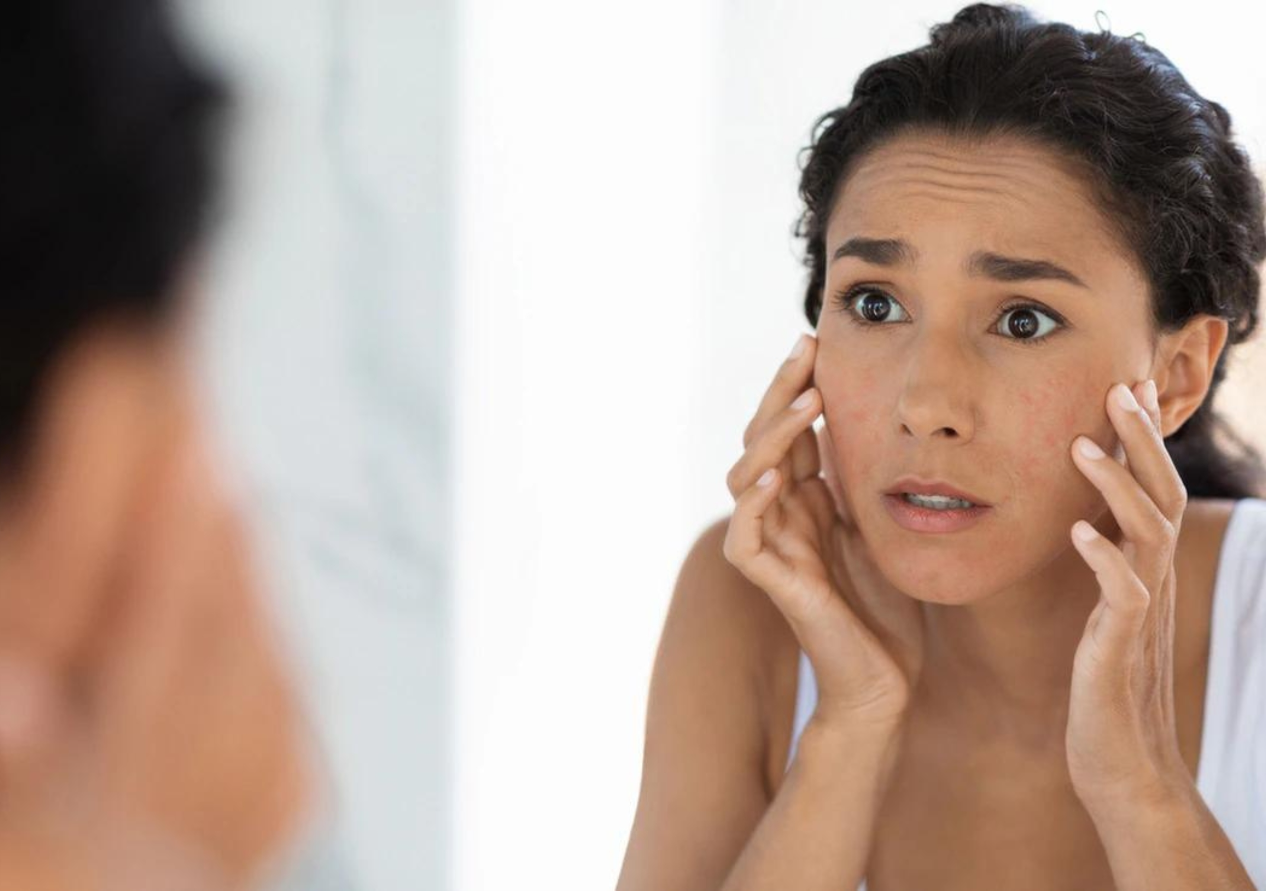 Woman with Worried Face is Looking at the Mirror while is Touching Her Face