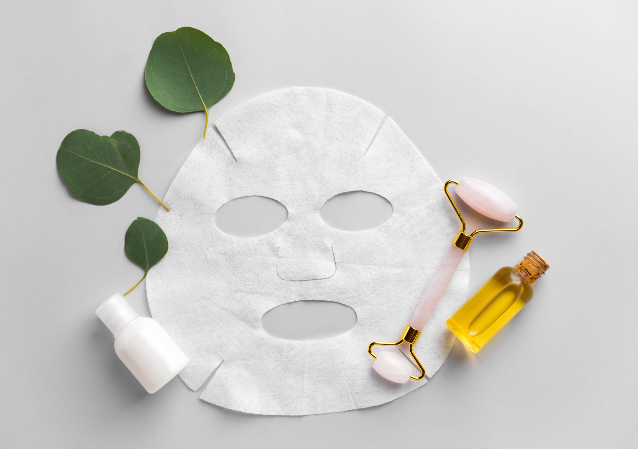 A Sheet Mask with a Derma Roller and Some Green Leaves