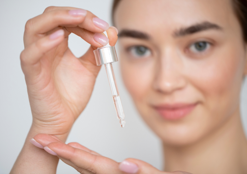 Beautiful Young Woman Dropping Face Serum on Hand