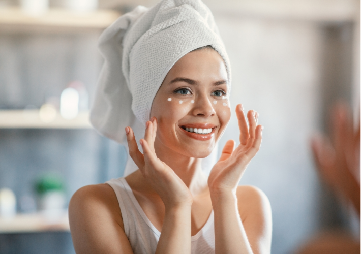 Happy Woman Looking at Mirror while Applying Face Cream