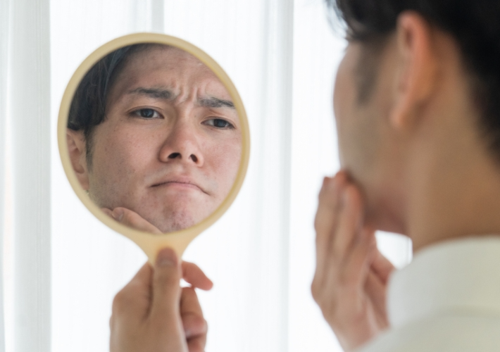 Sad Asian Man Looking into Mirror