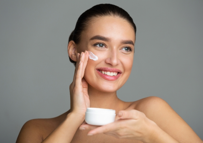 Smiling Woman Moisturizing her Face with Cream